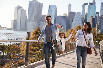 Young family with daughter taking a walk on footbridge
