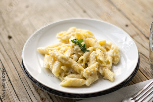 Homemade italian four cheese pasta on a white plate on a wooden table