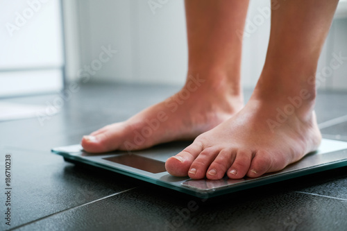 Female bare feet on the digital scale in the bathroom photo