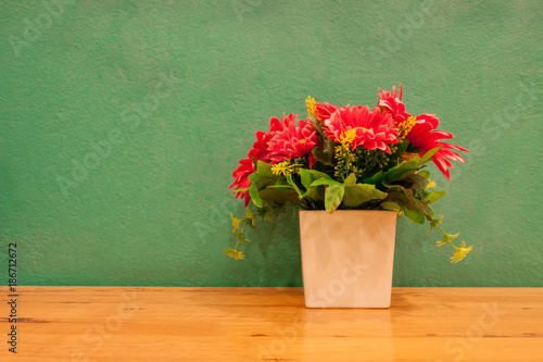 Fake flowers in pot with green background.