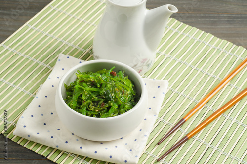 Spicy Seaweed Salad with chopsticks on bamboo background.