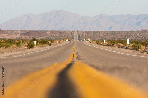 Classic horizontal panorama view of an endless straight road running through the barren scenery of the American Southwest on a beautiful day photo