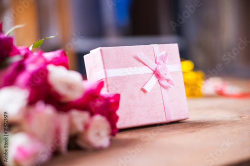 Pink gift box and flowers on the wooden table 