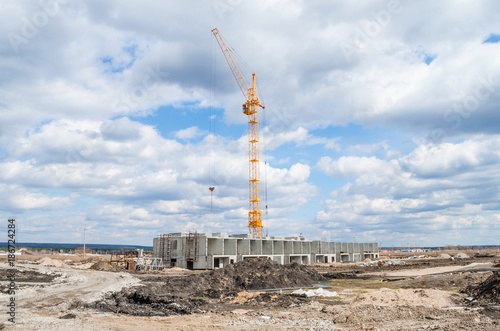 yellow construction crane operating in blue sky and white clouds