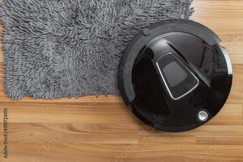 Robot vacuum cleaner on laminate wood floor with carpet cleaning photo