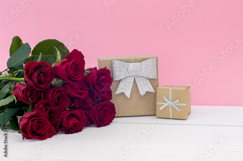 Beautiful red roses and gift glitter boxex on a white wooden surface photo