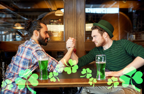 men drinking green beer and arm wrestling at pub