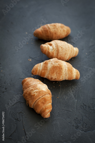 four croissants with a fruit filling, sprinkled with powdered sugar on a dark gray background