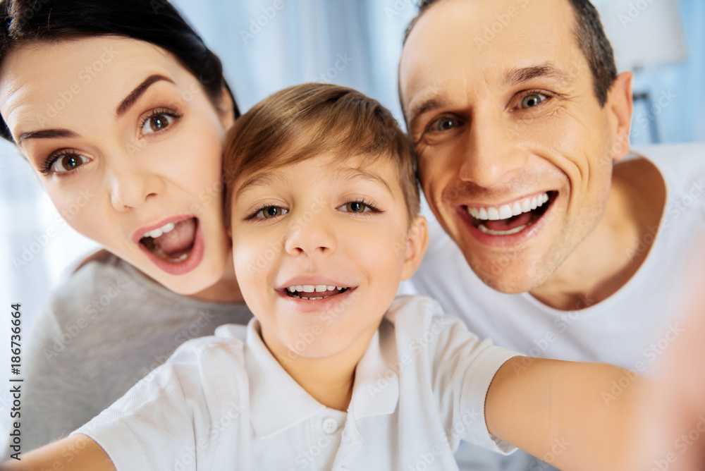 Perfect mood. The close up of a happy young family taking a selfie together, smiling at the camera and making funny faces Perfect mood. The close up of a happy young family taking a selfie together, smiling at the camera and making funny faces