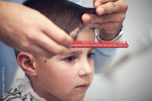 Caucasian boy  getting haircut in barbershop.