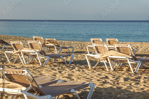 Sun loungers and closed umbrellas at a seaside resort , the calm and relaxed atmosphere of the summer holiday at sunset