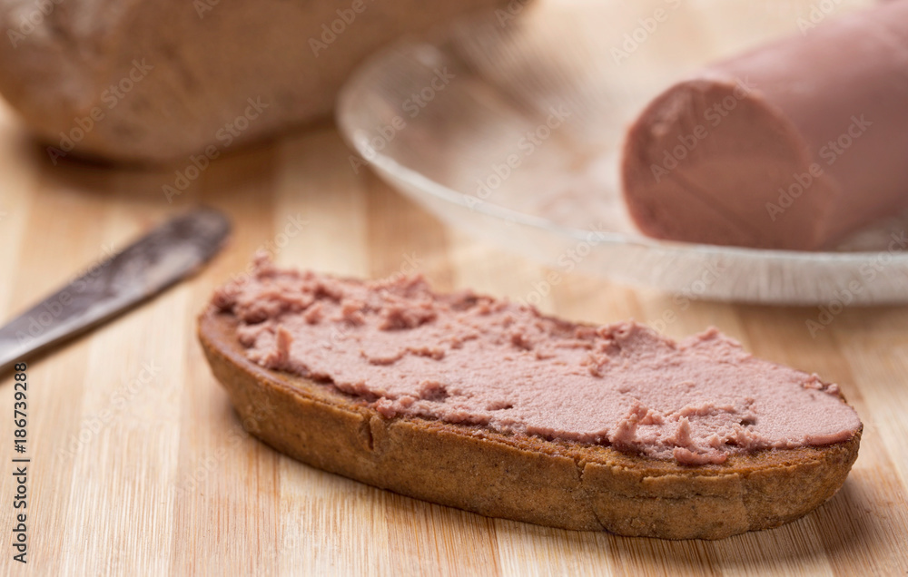 Liver spread on a slice of Rye bread with liver spread and Rye bread in background