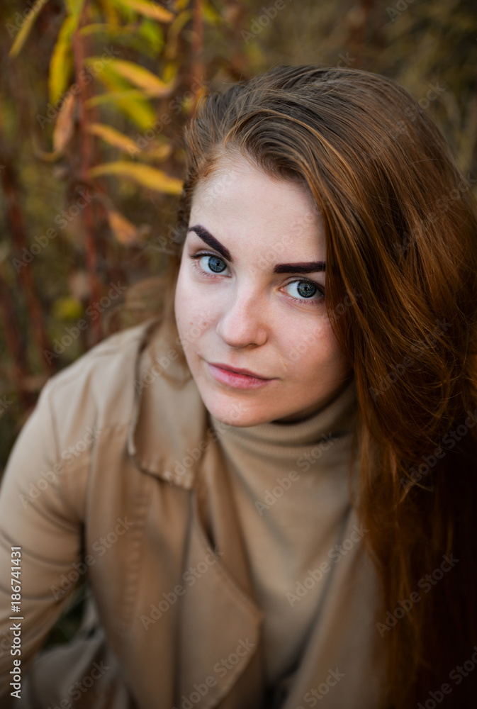 Stylish and beautiful red haired girl posing, walking in autumn forest among yellow grass. Woman with long hair, in jeans, blouse and brown coat, smiling, relaxing outdoors. Stylish and beautiful red haired girl posing, walking in autumn forest among yellow grass. Woman with long hair, in jeans, blouse and brown coat, smiling, relaxing outdoors.