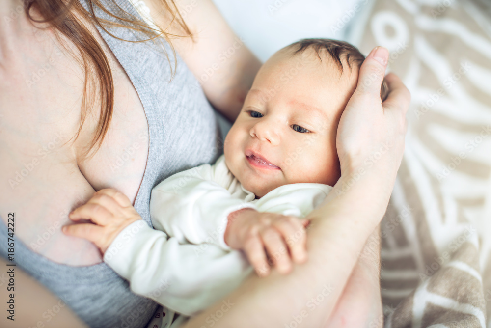 Happy caring mother holding a smiling baby boy in the bedroom. Concept of the tenderness of motherhood and family values Happy caring mother holding a smiling baby boy in the bedroom. Concept of the tenderness of motherhood and family values