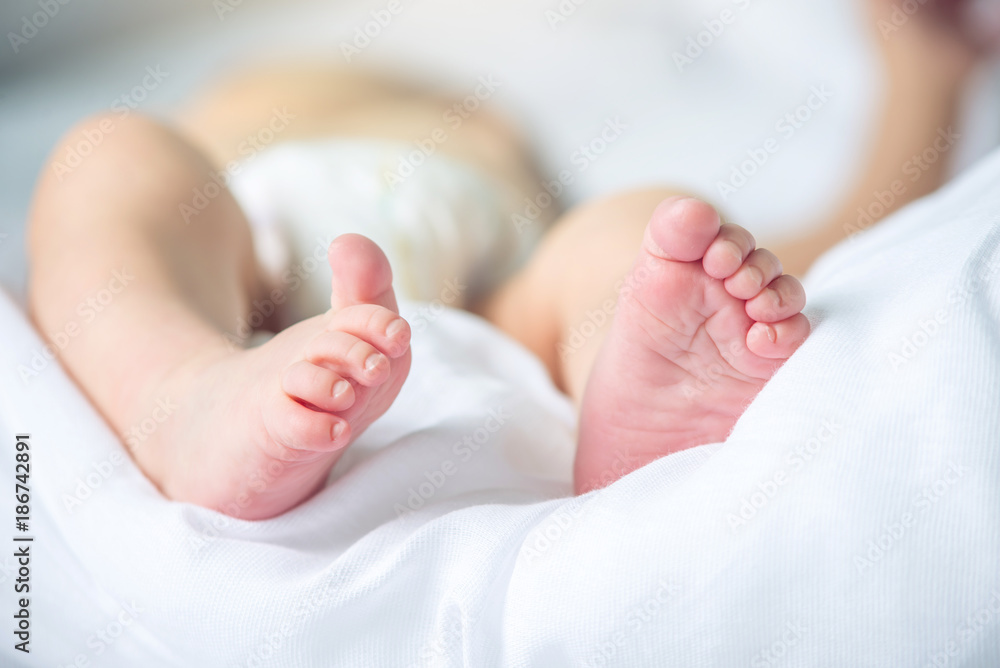 Baby feet with pink lying on a white blanket. Concept of tenderness and motherhood Baby feet with pink lying on a white blanket. Concept of tenderness and motherhood