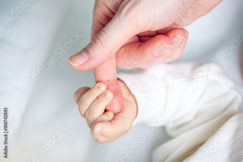 Baby boy holding mother's hand, squeezes the fingers. Concept of empathy, trust, care and tenderness of motherhood