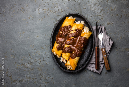 Mexican cuisine. Traditional Mexican chicken enchiladas with spicy chocolate salsa mole poblano. Enchiladas with sauce moole from Puebla, Mexico