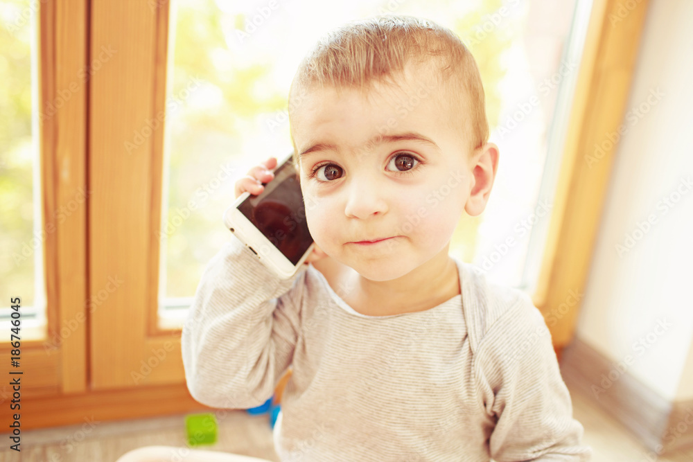 Disappointed toddler with phone in his hand. Missing mom concept Disappointed toddler with phone in his hand. Missing mom concept