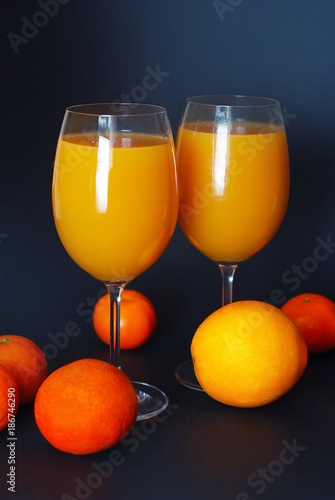Orange Juice in Glasses with citrus fruits on dark blue background. Vertical Image. photo