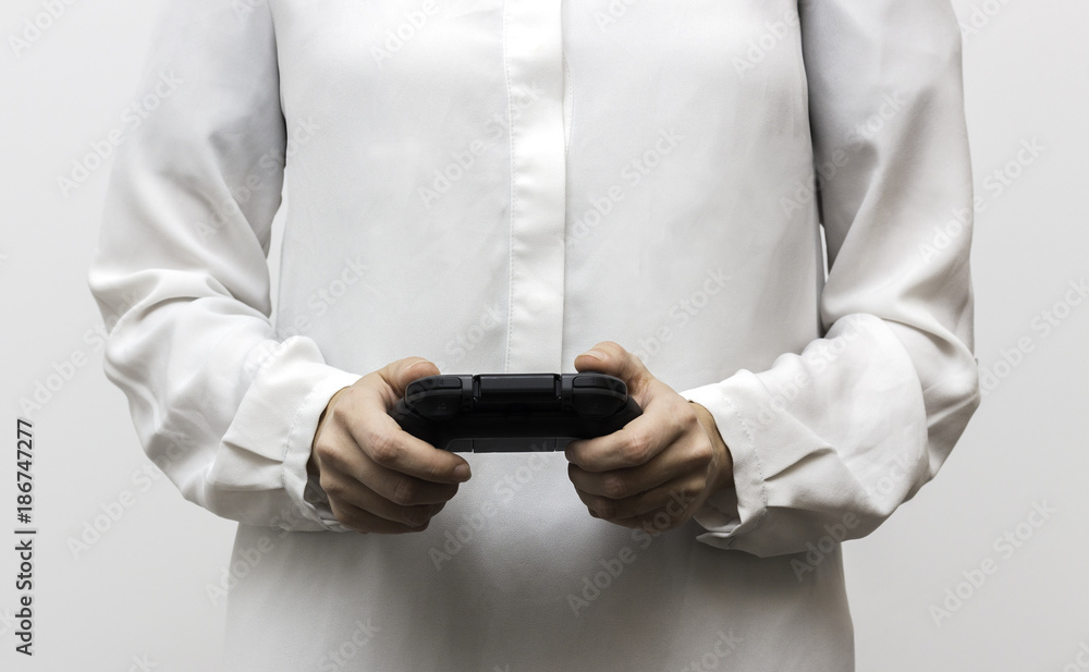 Black gamepad in the woman's hands on the white background. Gaming video game. Selective focus and shallow DOF Black gamepad in the woman's hands on the white background. Gaming video game. Selective focus and shallow DOF