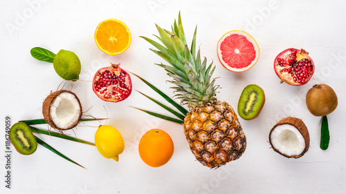 Fototapeta Naklejka Na Ścianę i Meble -  Fresh Tropical Fruits. Pineapple, coconut, kiwi, orange, pomegranate, grapefruit. On a wooden background. Top view. Free space for text.