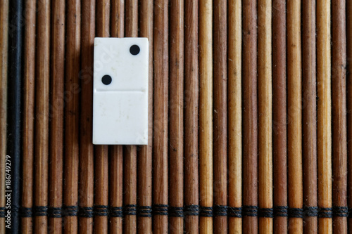 Domino piece on the bamboo brown wooden table background. Domino set empty - 2 dots. photo