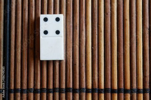 Domino piece on the bamboo brown wooden table background. Domino set empty - 4 dots. photo