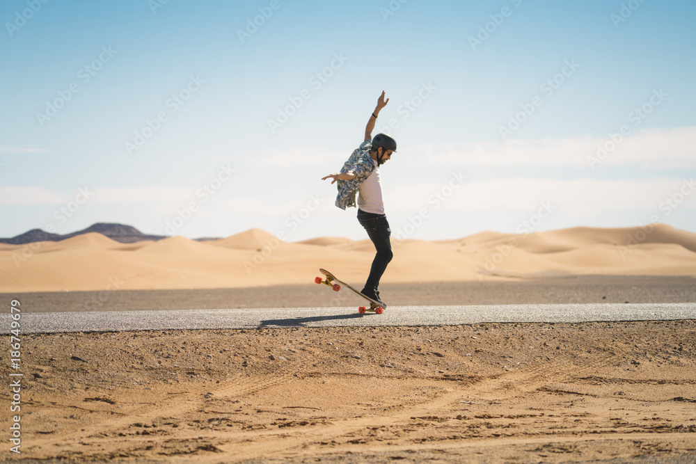 Side view of man skateboarding on road against blue sky during sunny day Side view of man skateboarding on road against blue sky during sunny day