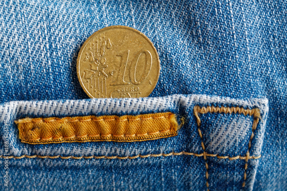 Euro coin with a denomination of ten euro cent in the pocket of worn blue denim jeans with orange laces Euro coin with a denomination of ten euro cent in the pocket of worn blue denim jeans with orange laces