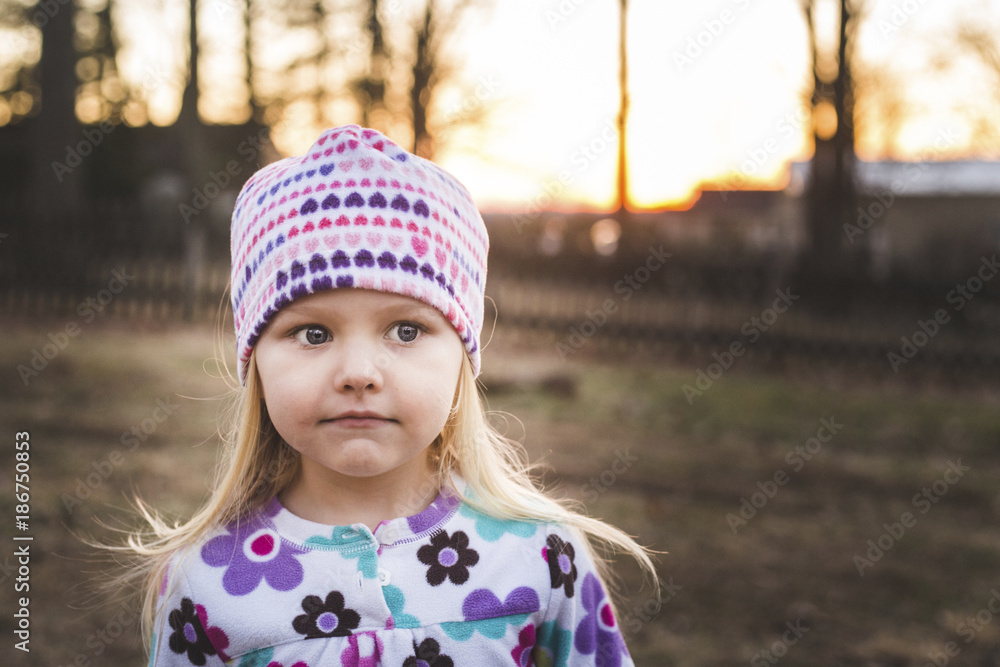 Close-up of girl looking away while standing on field during sunset Close-up of girl looking away while standing on field during sunset