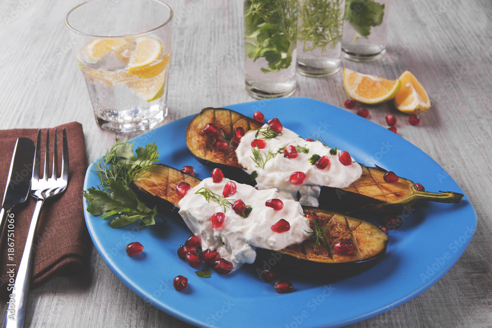  baked eggplants on a plate with cream cheese and pomegranate seeds