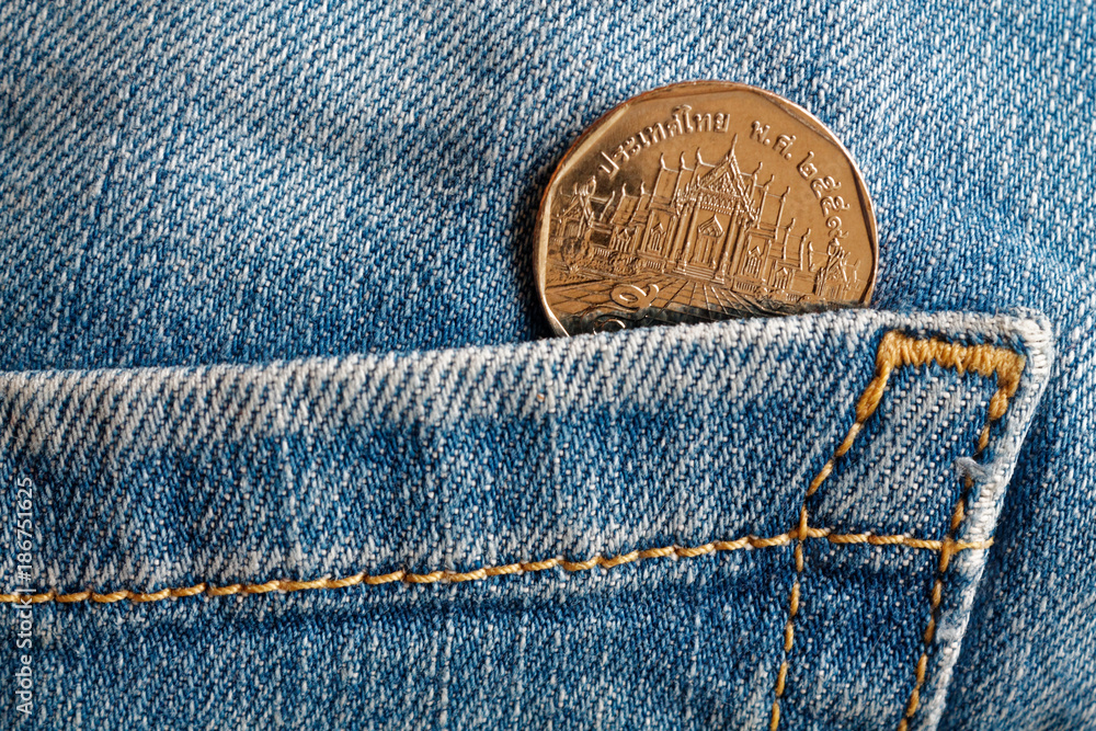 Thai coin with a denomination of five baht in the pocket of old blue worn denim jeans Thai coin with a denomination of five baht in the pocket of old blue worn denim jeans