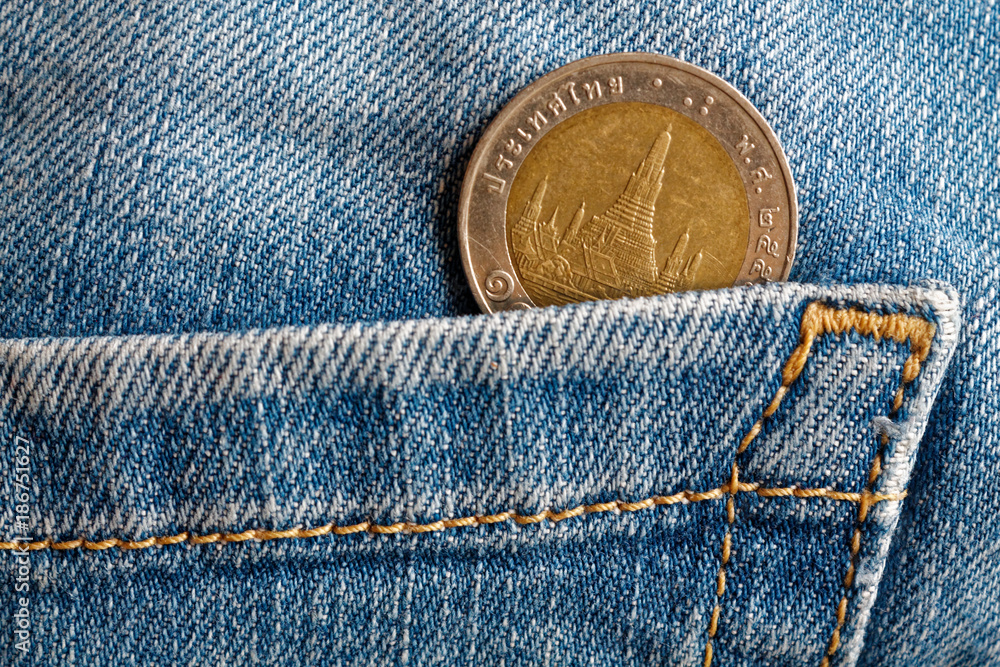 Thai coin with a denomination of ten baht in the pocket of old blue worn denim jeans Thai coin with a denomination of ten baht in the pocket of old blue worn denim jeans