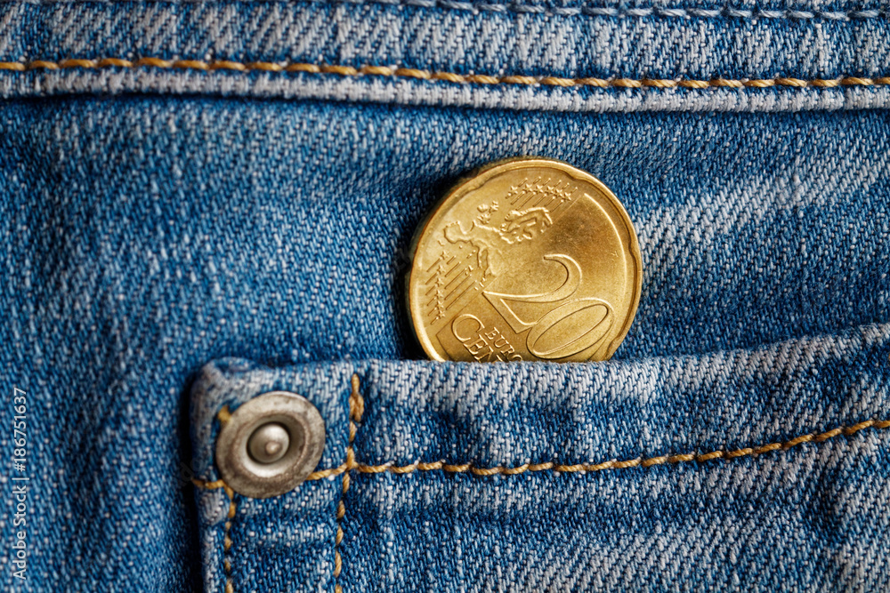 Euro coin with a denomination of 20 euro cents in the pocket of light blue denim jeans Euro coin with a denomination of 20 euro cents in the pocket of light blue denim jeans