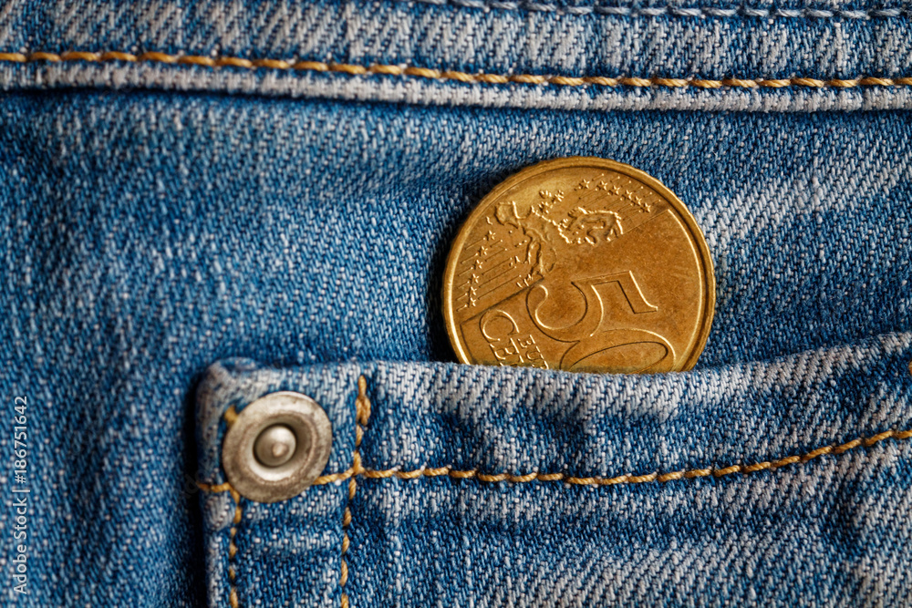 Euro coin with a denomination of 50 euro cents in the pocket of light blue denim jeans Euro coin with a denomination of 50 euro cents in the pocket of light blue denim jeans