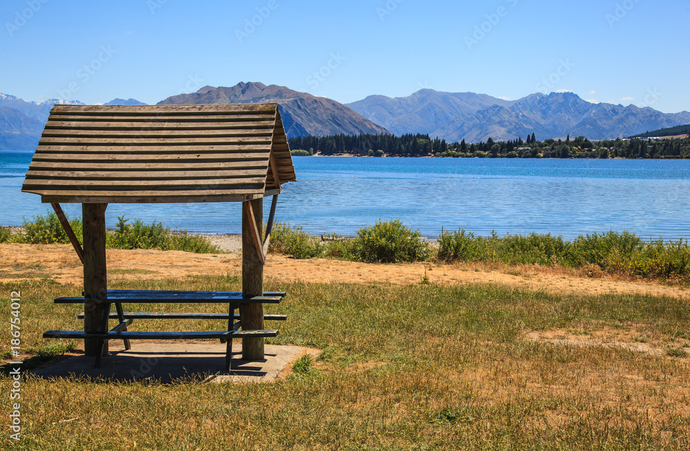 Summer day view of Shade shelter for tourists at Lake Wanaka, New Zealand with blue lake and mountain background. Summer day view of Shade shelter for tourists at Lake Wanaka, New Zealand with blue lake and mountain background.