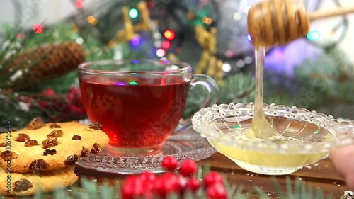 a cup of tea with honey and cookies, a branch of a Christmas tree in the snow, Christmas lights