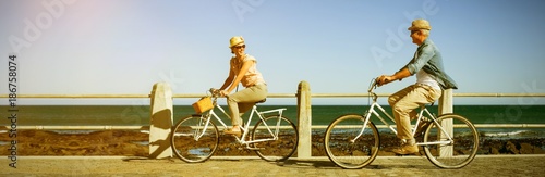 Obraz na plátne Happy couple riding bicycles on pier