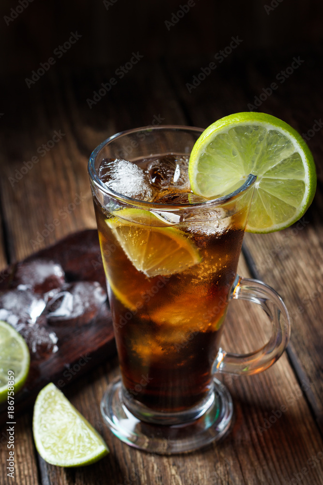 Rum and cola Cuba Libre drink with brown rum, cola, ice and lime on rustic wooden table Rum and cola Cuba Libre drink with brown rum, cola, ice and lime on rustic wooden table