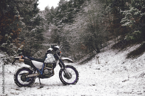 Motorcycle in a winter forest snow on the background of snowy trees. Winter extreme fun. Motorcycling in the winter. extreme fun in winter on a motorbike  enduro off road dual sport travel