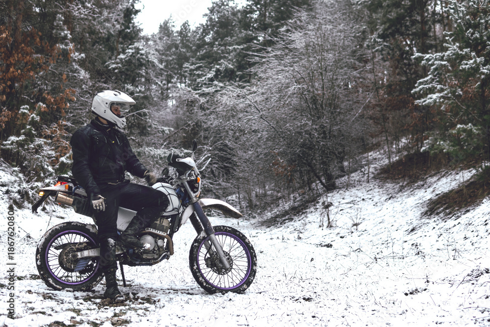 Rider man on a motorcycle Winter motocross. Skid on a snowy forest. the snow from under the wheels of a motorcycle Enduro. off road dual sport travel tour, active life style concept