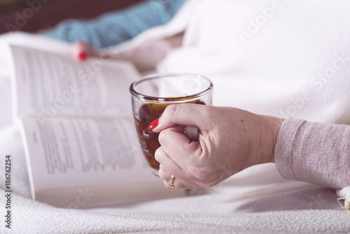 women drink tea and read a book wrapped in blankets