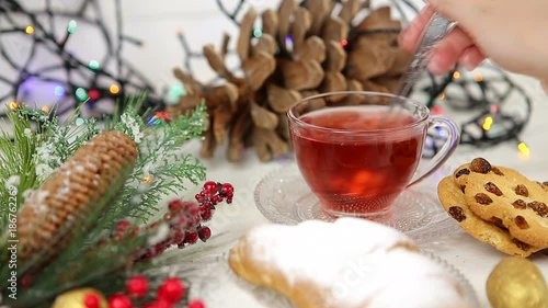 a cup of tea with honey and croissant , a branch of a Christmas tree in the snow, Christmas lights