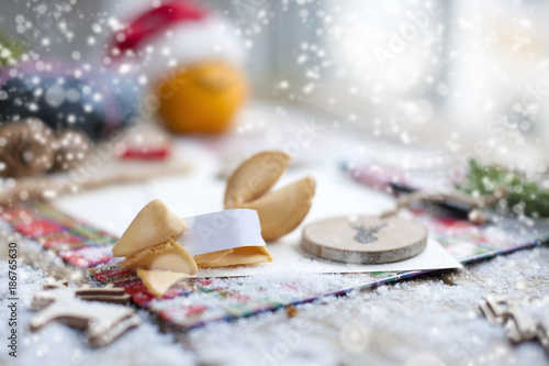 traditional cookies with wishes for Christmas and New Year, on the table with decor near the window and falling snow