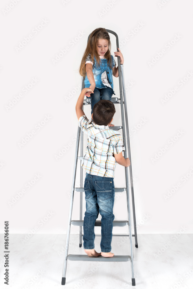 the boy helps the girl to go down on  a ladder