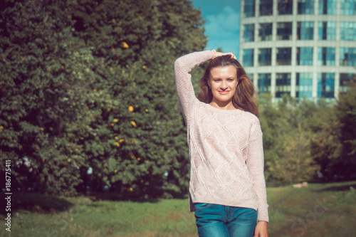 Beautiful young woman straightens hair in the park