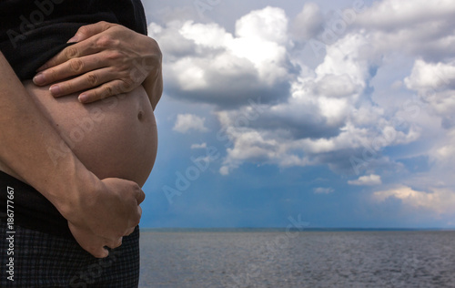 pregnant woman stroking her belly at sunset.