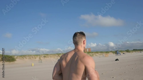 Young man running on the beach at sunny day