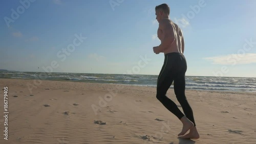 Sport man athlete running shirtless on beautiful beach.