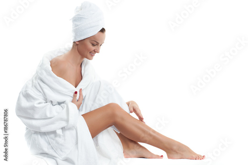 Beautiful girl in bathrobe is touching her legs. Depilation and bodycare concept